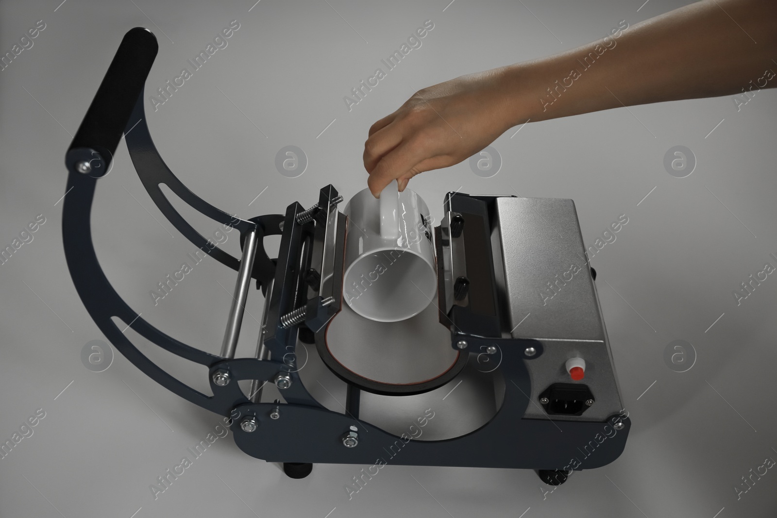 Photo of Printing logo. Woman with mug using heat press at white table, closeup