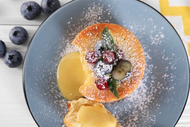 Tasty vanilla fondant with white chocolate and berries on light wooden table, flat lay