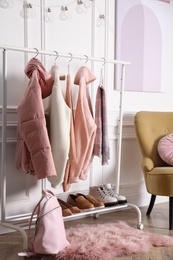 Rack with stylish warm clothes, shoes and accessories in modern dressing room