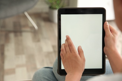 Photo of Woman working with modern tablet indoors, closeup. Space for design