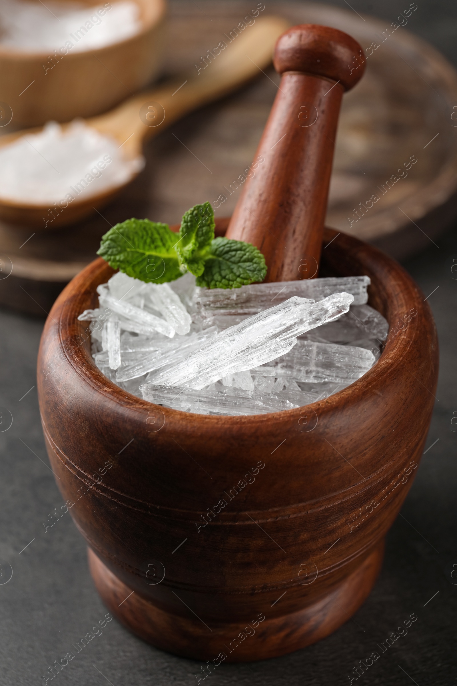 Photo of Menthol crystals and mint leaves in mortar on grey background