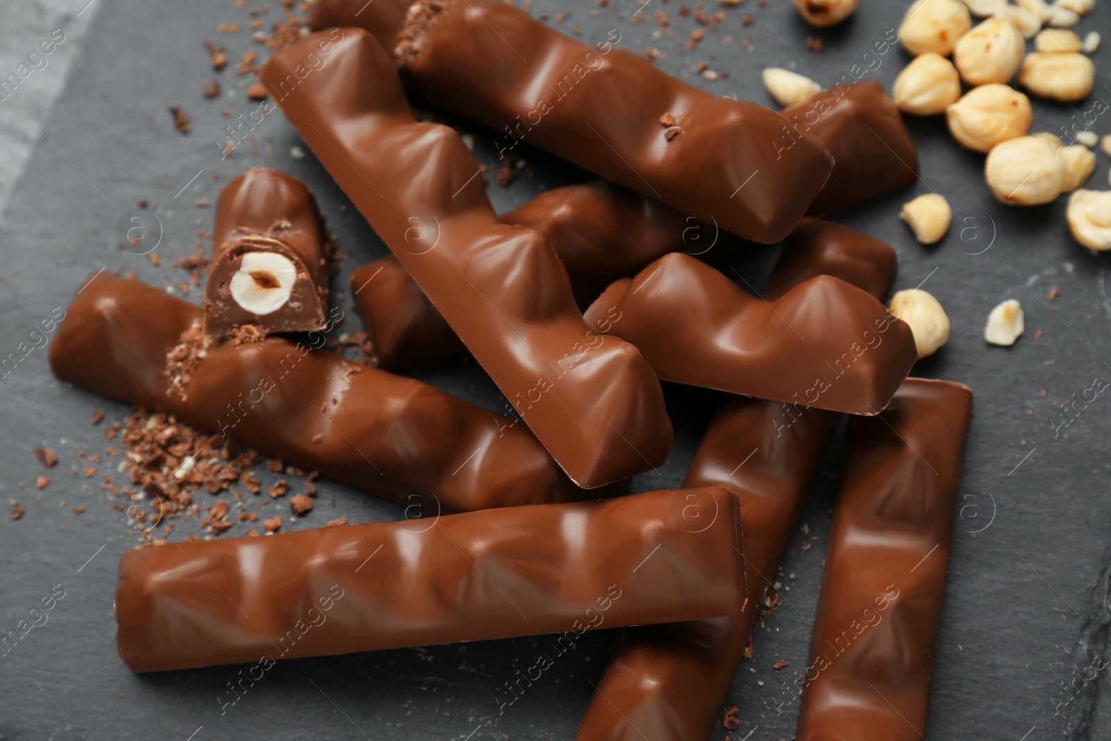 Photo of Tasty chocolate bars with nuts on black table, above view