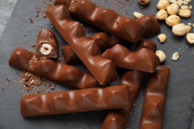 Photo of Tasty chocolate bars with nuts on black table, above view