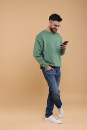 Handsome young man using smartphone on beige background