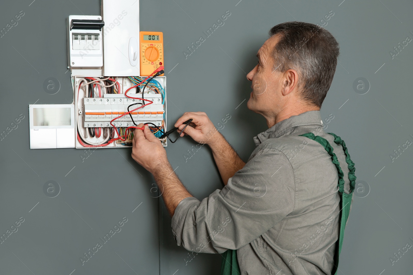 Photo of Professional electrician with tester checking voltage indoors