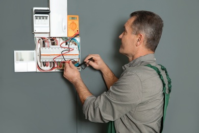 Photo of Professional electrician with tester checking voltage indoors