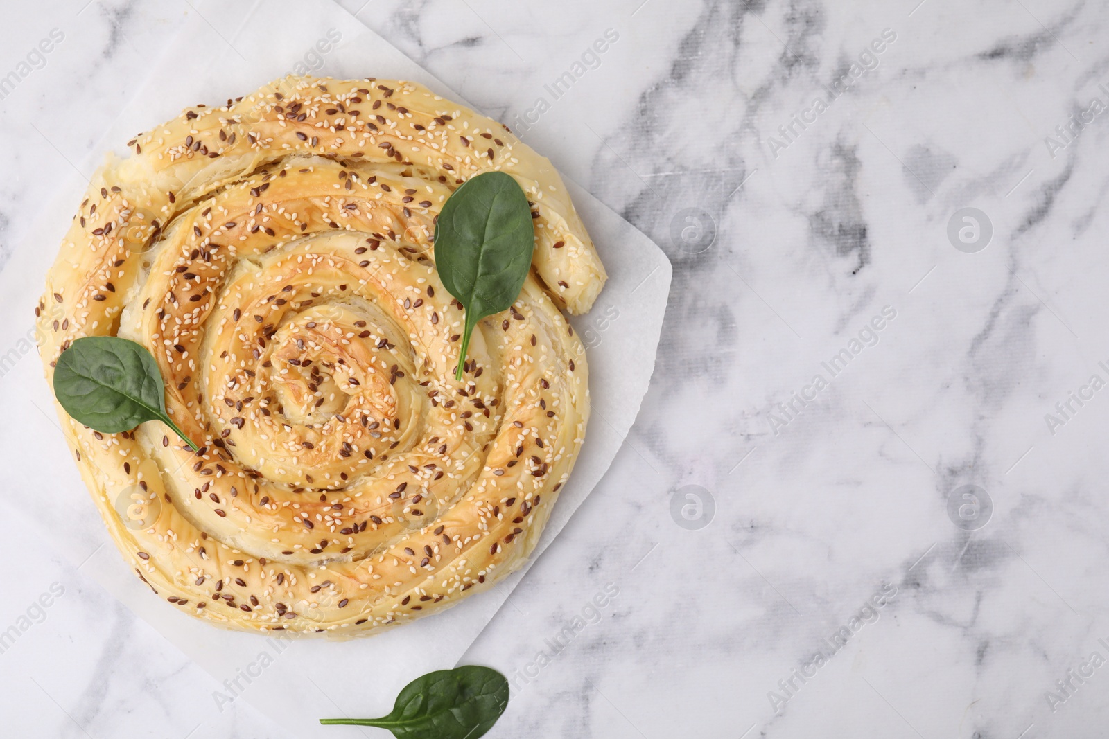 Photo of Delicious puff pastry with spinach on white marble table, top view. Space for text