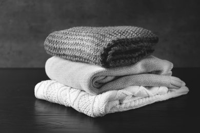 Photo of Stack of warm knitted clothes on table