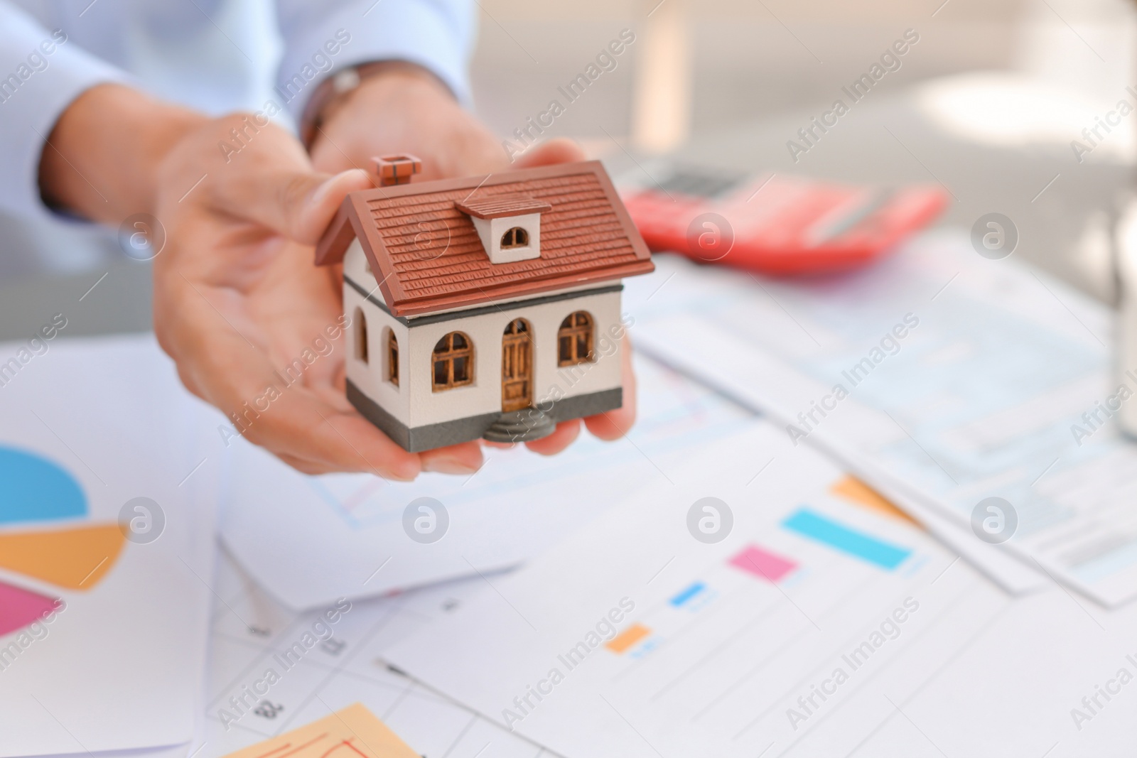 Photo of Man holding house model at table, closeup. Property tax
