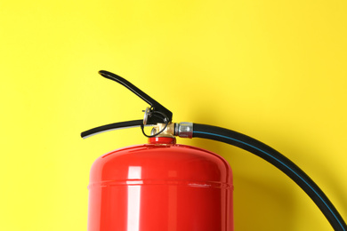 Fire extinguisher on yellow background, top view