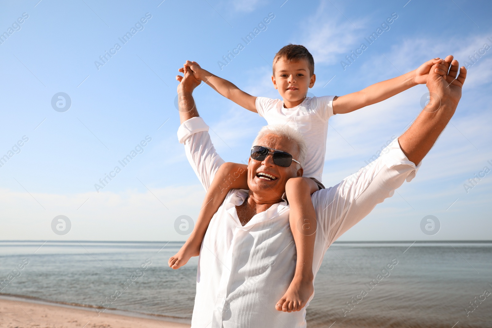 Photo of Cute little boy with grandfather spending time together on sea beach