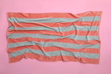 Photo of Crumpled striped beach towel on pink background, top view