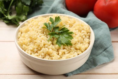 Delicious bulgur with parsley in bowl on table, closeup