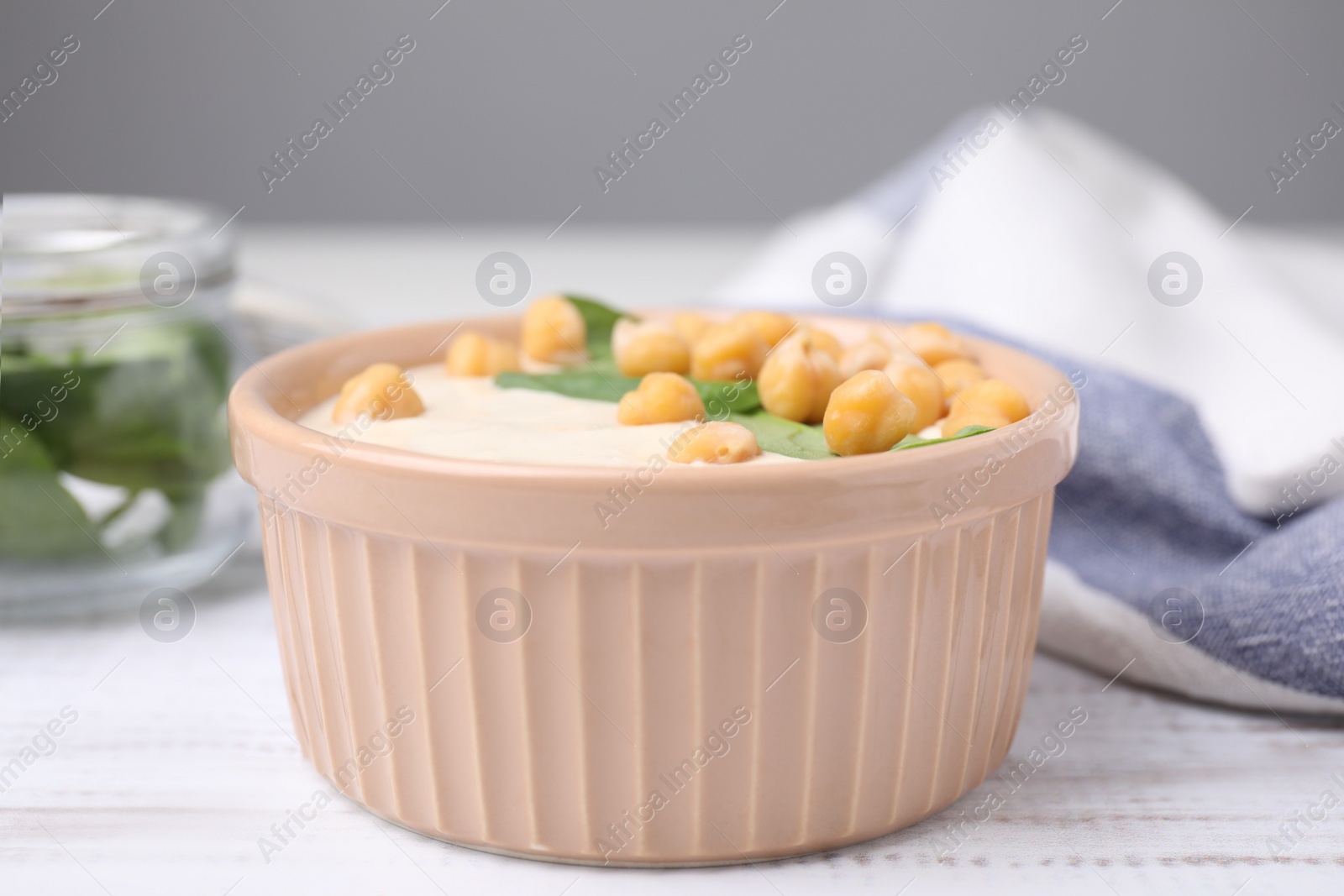 Photo of Tasty chickpea soup in bowl on white wooden table, closeup