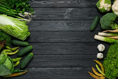 Photo of Frame made of different fresh ripe vegetables on black wooden table, flat lay with space for text. Farmer produce