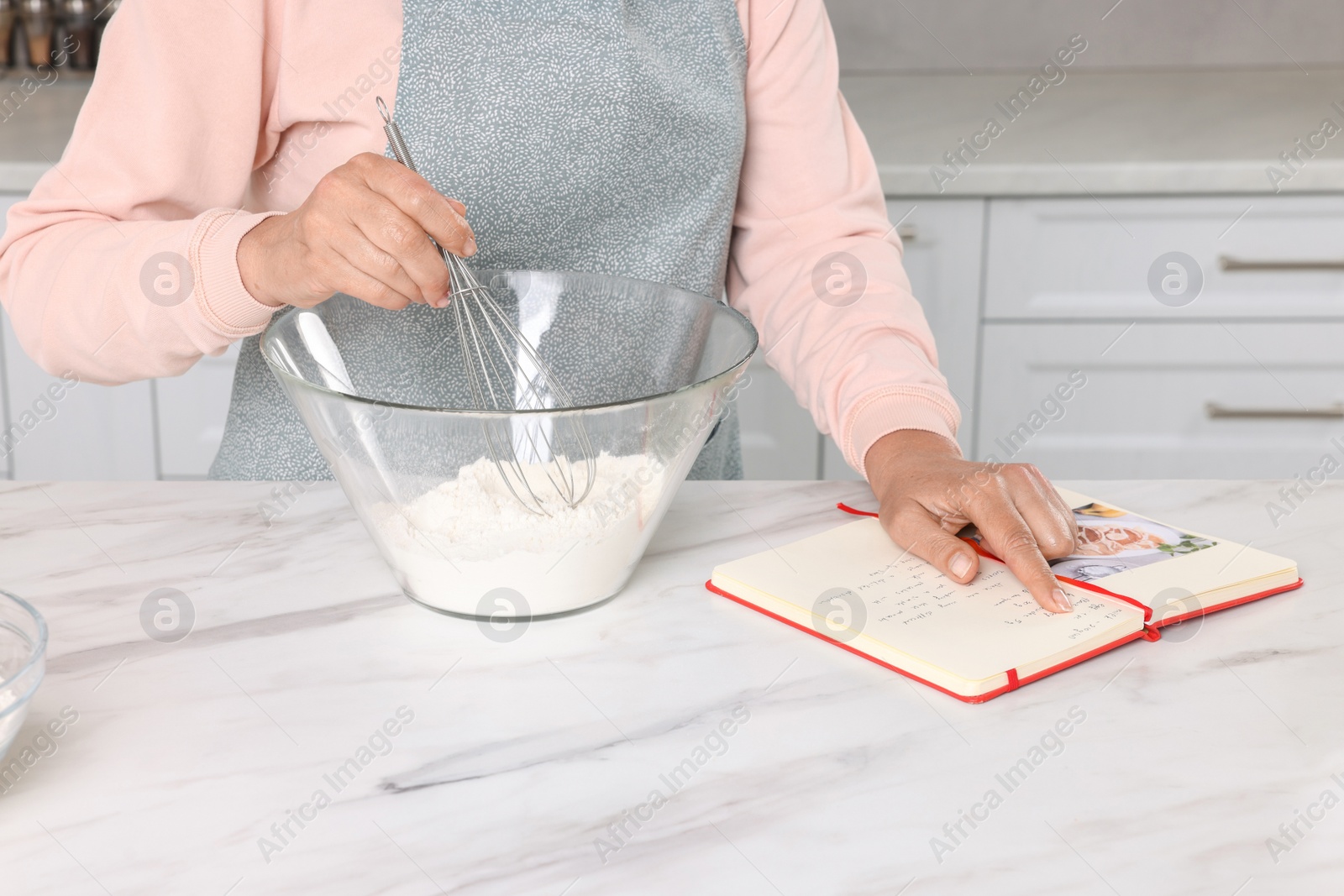 Photo of Woman with recipe book cooking in kitchen, closeup