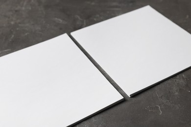 Blank paper sheets on grey textured table, closeup. Mockup for design