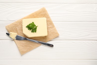 Tasty butter and knife on white wooden table, top view. Space for text