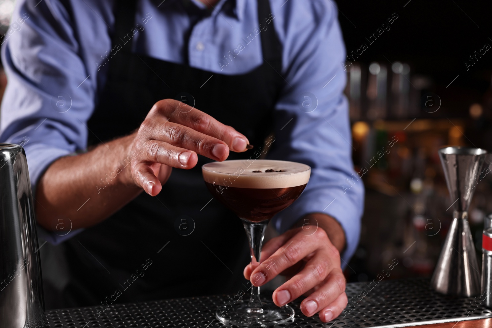 Photo of Bartender preparing Espresso Martini in bar, closeup. Alcohol cocktail