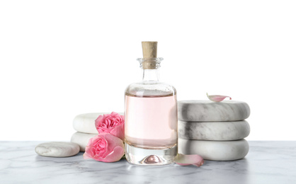 Photo of Bottle of essential oil, flowers and stones on marble table
