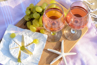 Photo of Glasses with rose wine and snacks on picnic blanket, above view