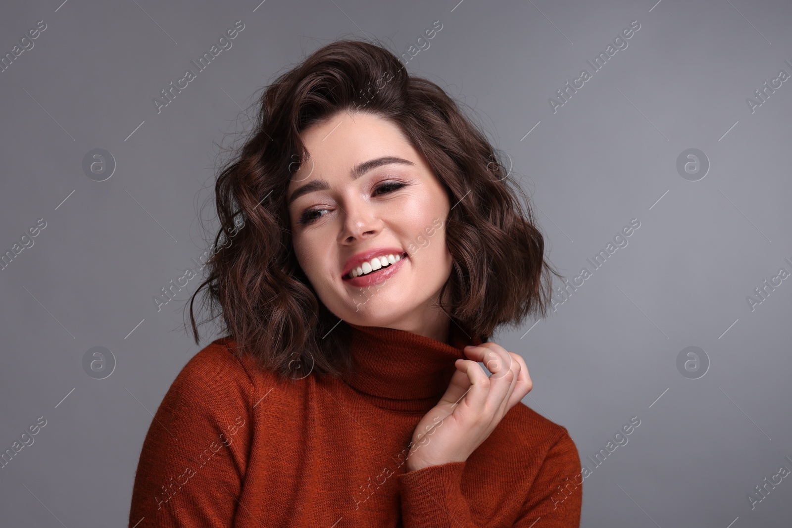 Photo of Portrait of beautiful young woman with wavy hairstyle on grey background