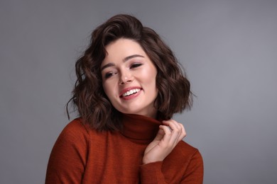 Photo of Portrait of beautiful young woman with wavy hairstyle on grey background