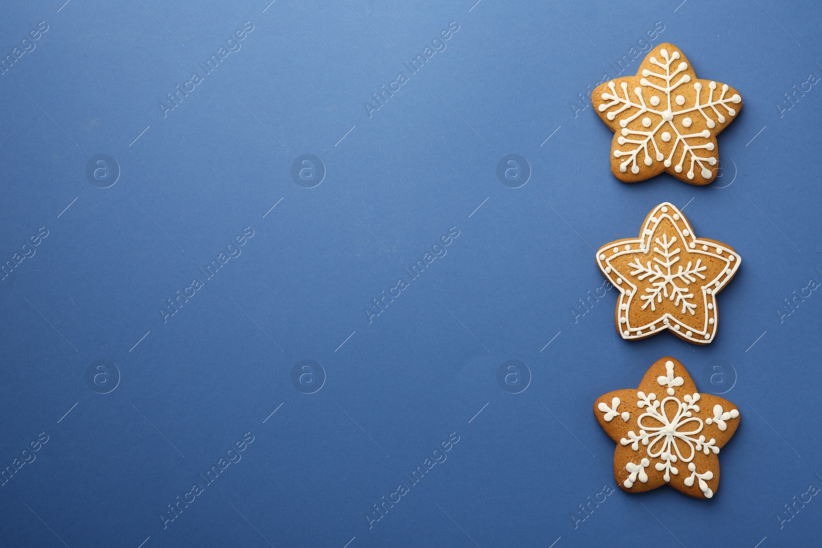 Photo of Tasty star shaped Christmas cookies with icing on blue background, flat lay. Space for text