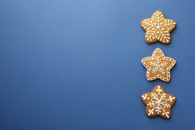 Photo of Tasty star shaped Christmas cookies with icing on blue background, flat lay. Space for text