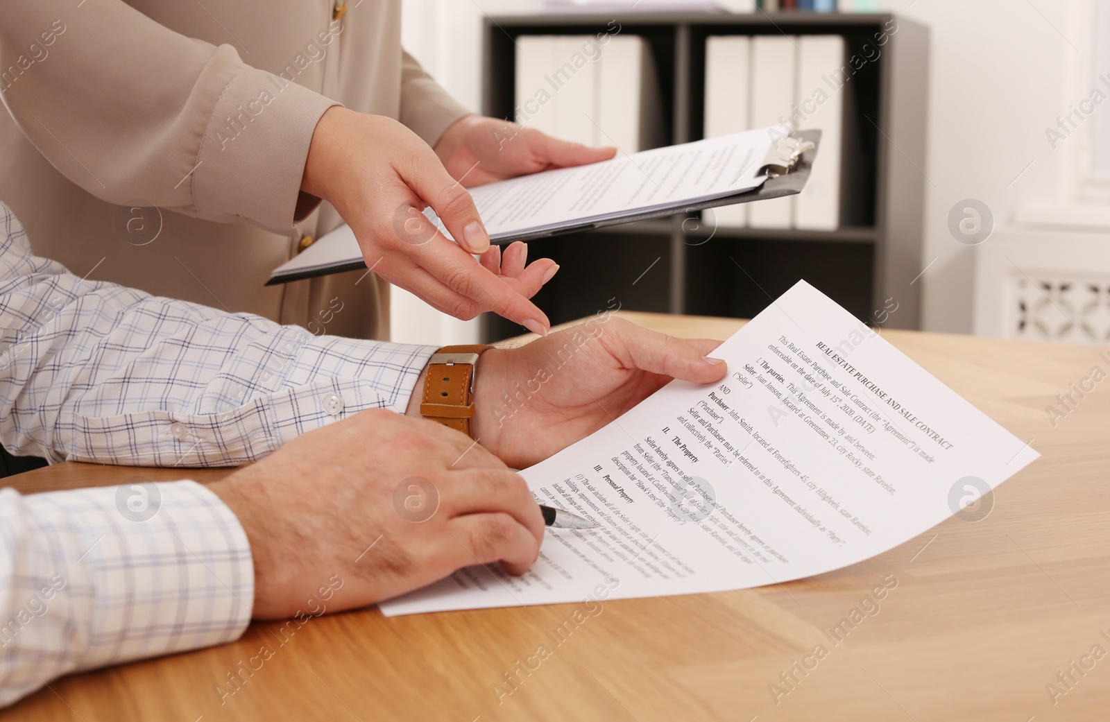 Photo of Businesspeople signing contract at wooden table indoors, closeup of hands