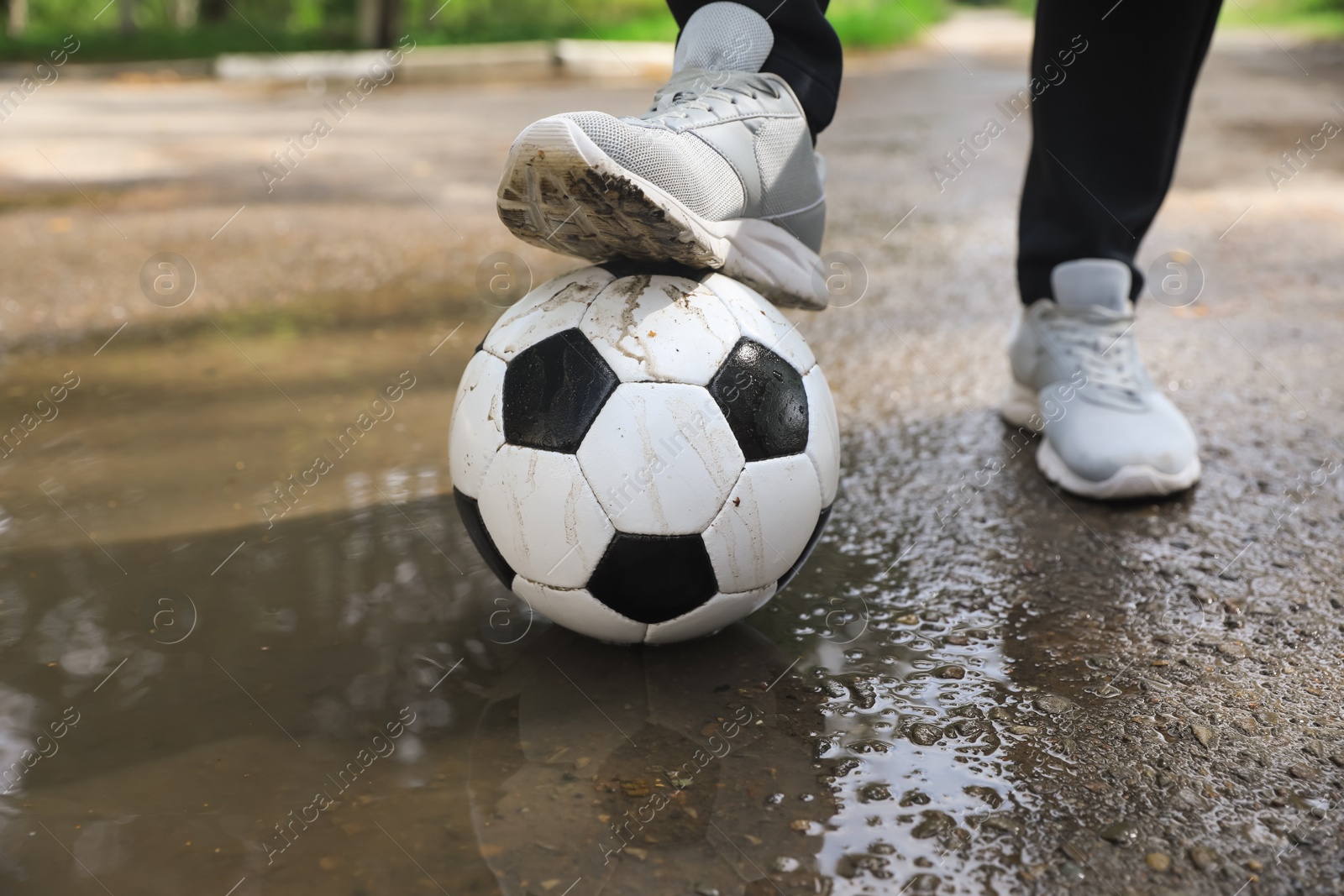 Photo of Man with soccer ball near puddle outdoors, closeup