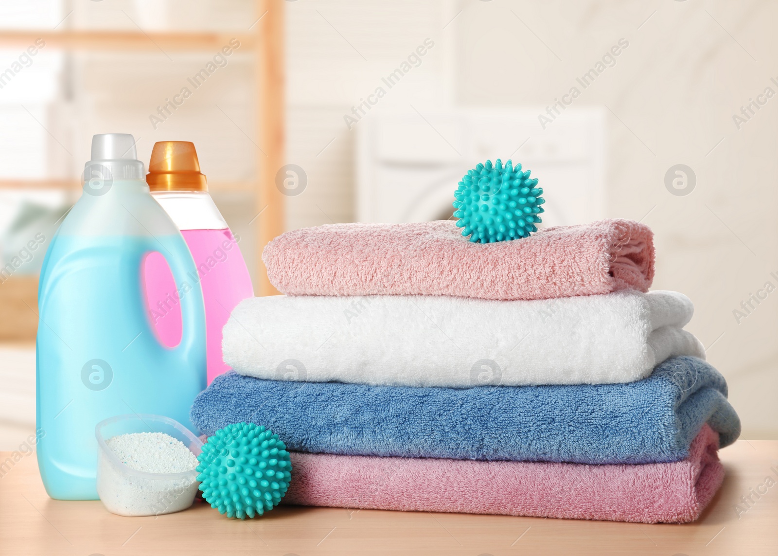 Image of Dryer balls, detergents and stacked clean towels on wooden table in laundry room