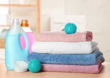 Image of Dryer balls, detergents and stacked clean towels on wooden table in laundry room