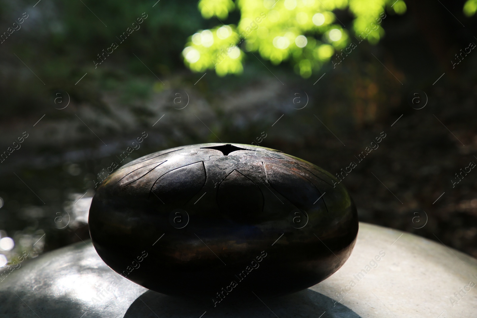 Photo of Steel tongue drum on stone outdoors. Percussion musical instrument