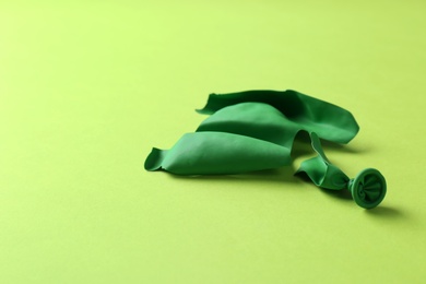 Photo of Popped green latex balloon on color background