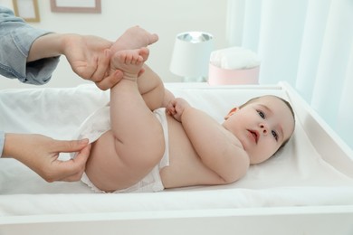 Photo of Mother changing baby's diaper on table at home