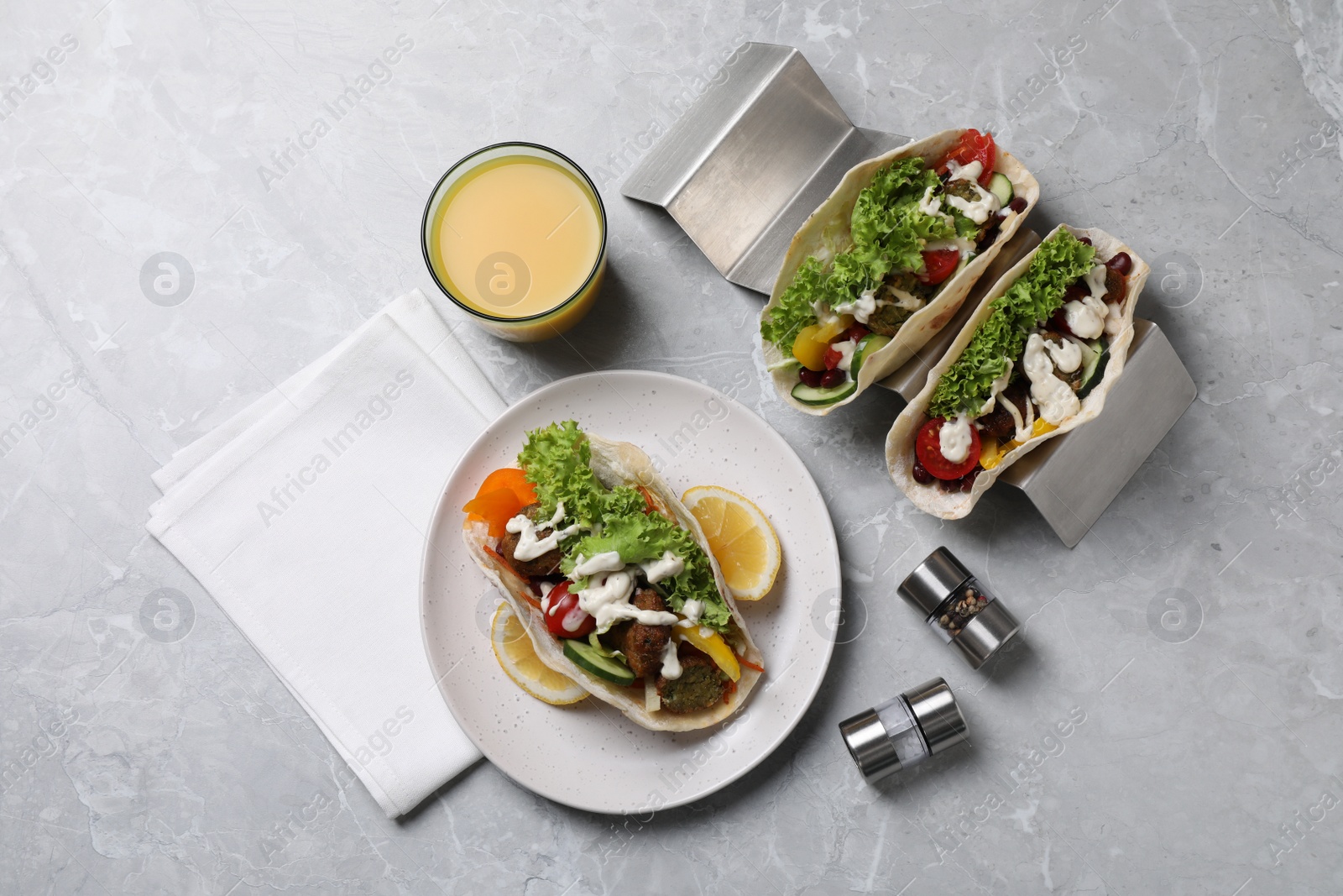 Photo of Delicious fresh vegan tacos served on light grey marble table, flat lay