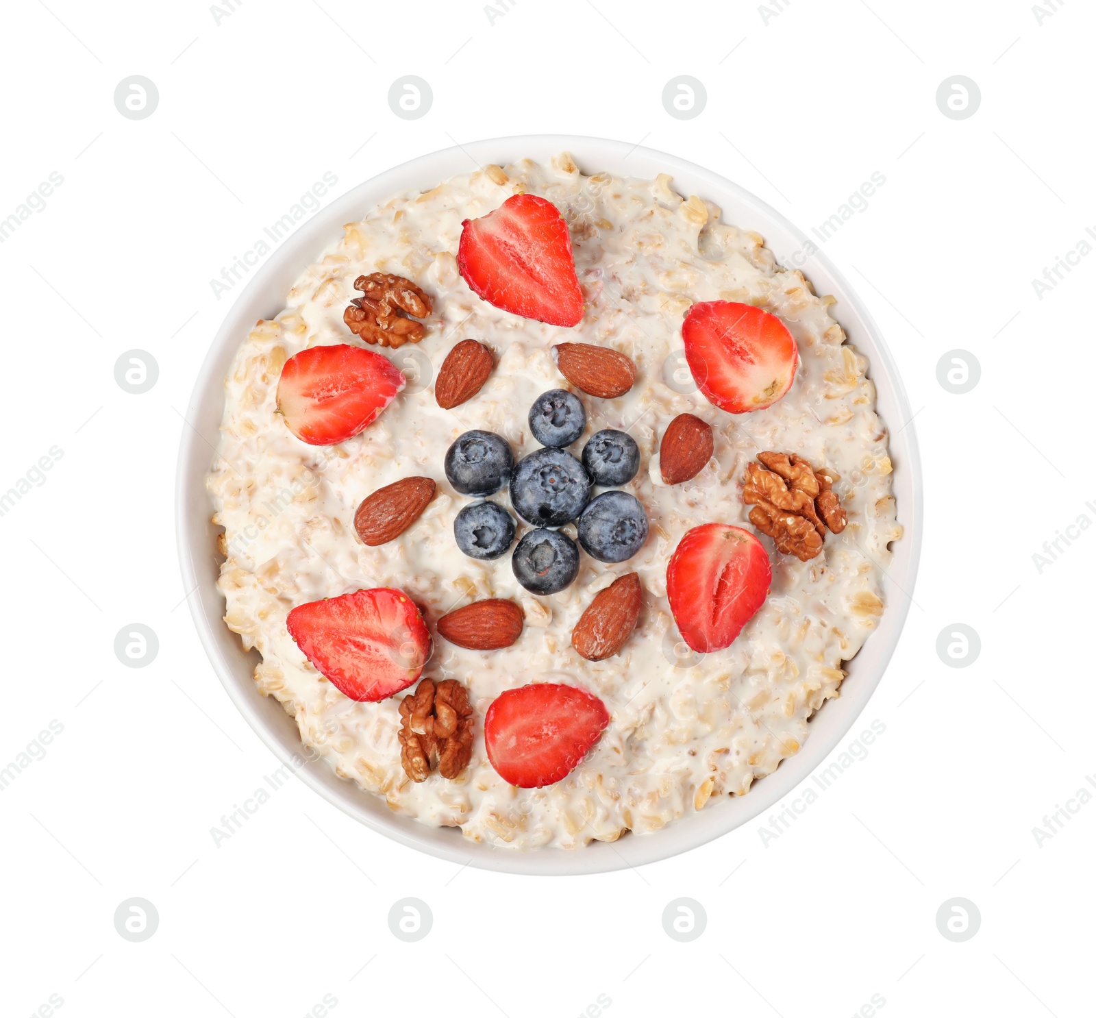 Photo of Tasty boiled oatmeal with berries and nuts in bowl isolated on white, top view