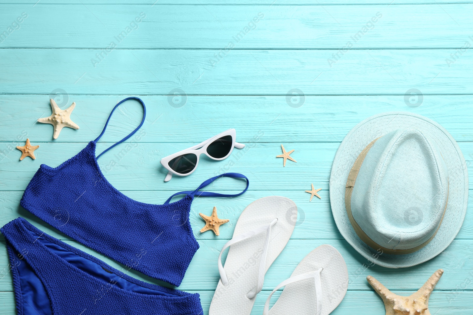 Photo of Swimsuit and beach accessories on light blue wooden table, flat lay. Space for text