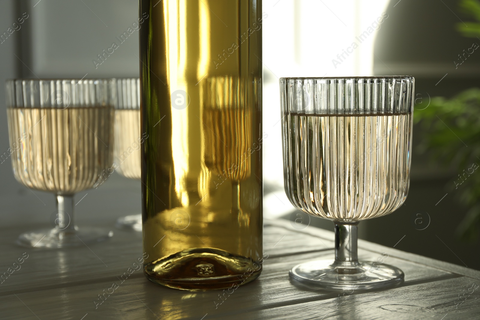 Photo of Alcohol drink in glasses and bottle on wooden table indoors, closeup