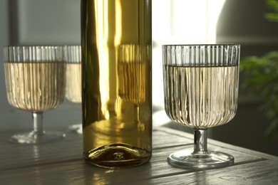 Photo of Alcohol drink in glasses and bottle on wooden table indoors, closeup