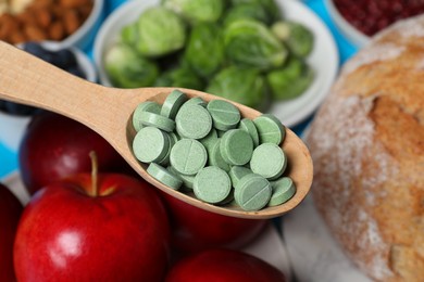 Photo of Holding spoon with prebiotic pills over food, closeup