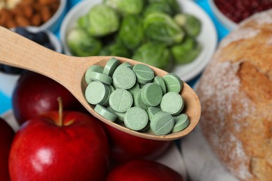 Holding spoon with prebiotic pills over food, closeup