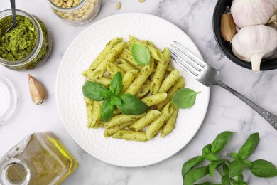 Delicious pasta with pesto sauce and ingredients on white marble table, flat lay