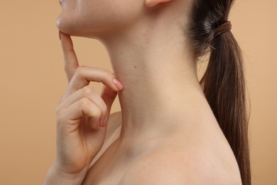 Photo of Woman touching her chin on beige background, closeup