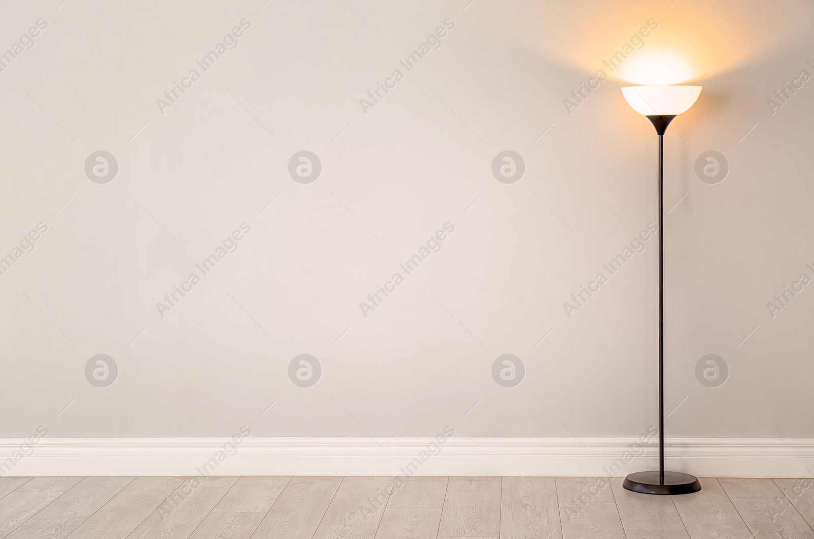 Photo of Modern floor lamp against light wall indoors. Space for text