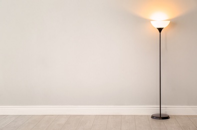 Photo of Modern floor lamp against light wall indoors. Space for text