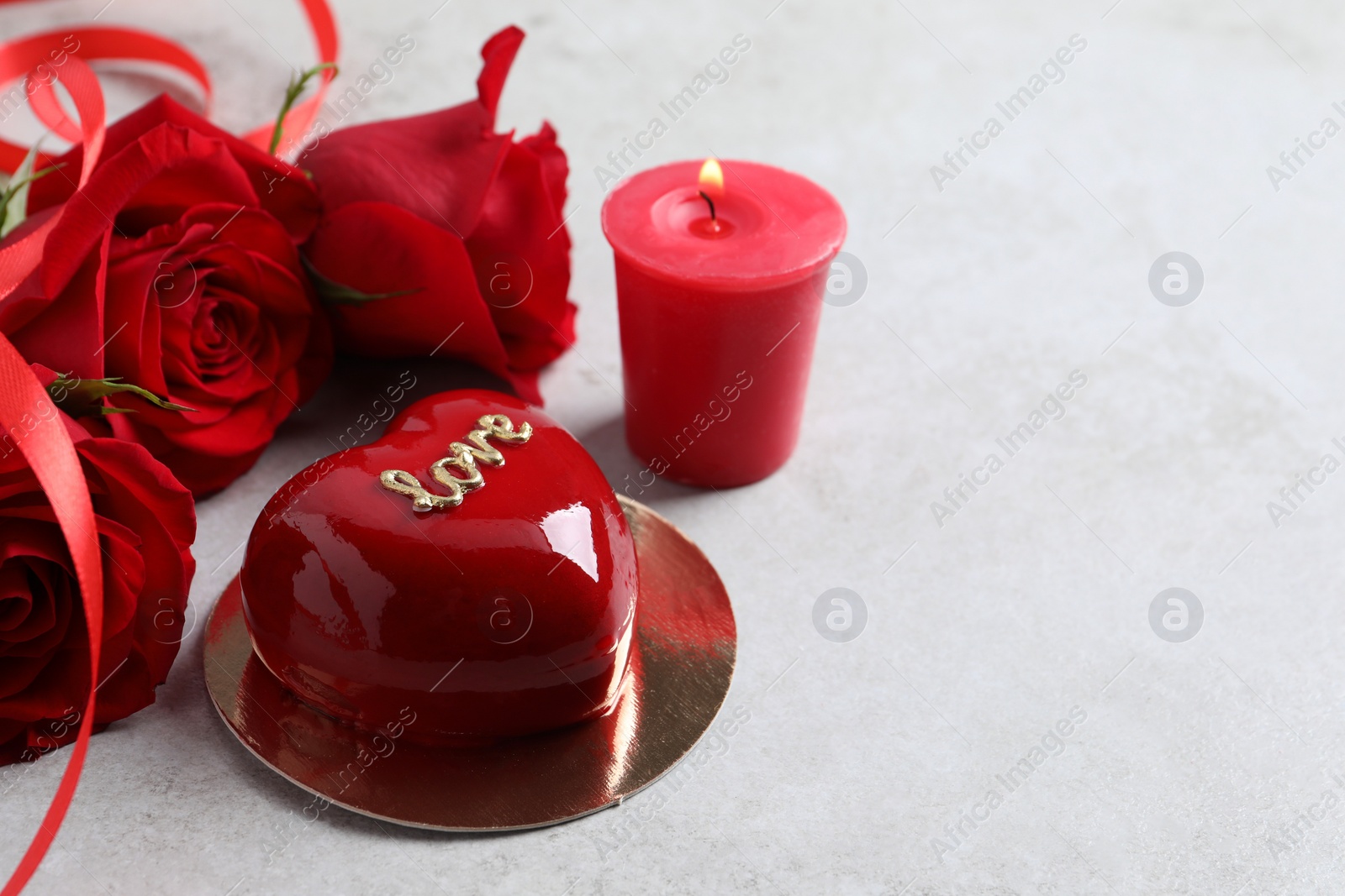 Photo of St. Valentine's Day. Delicious heart shaped cake, roses and candle on light table, closeup. Space for text
