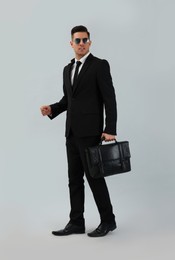 Businessman with stylish leather briefcase on light background