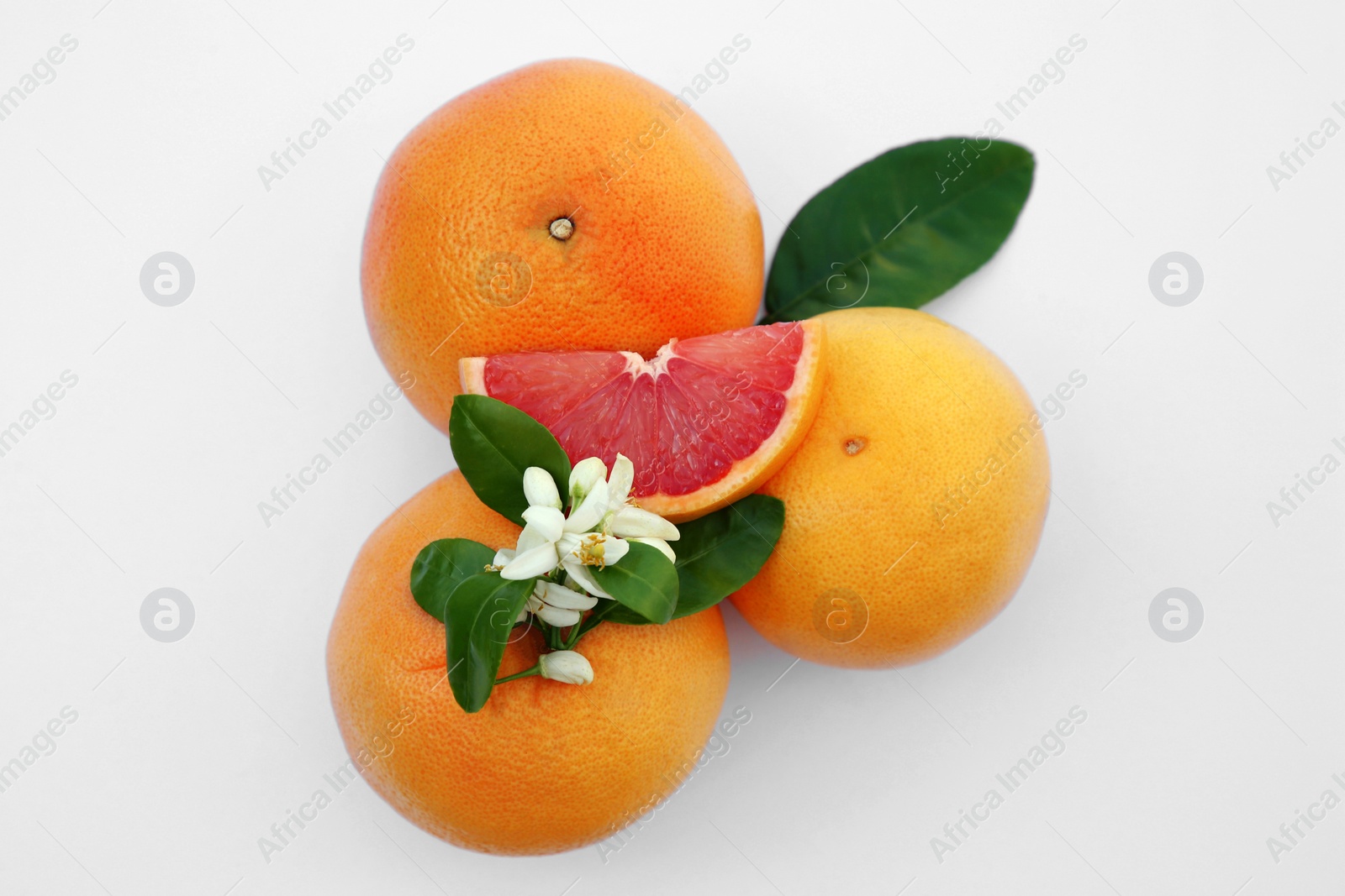 Photo of Fresh ripe grapefruits and green leaves on white background, top view